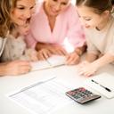 Family looking at a planning worksheet with a notebook and calculator in soft daylight